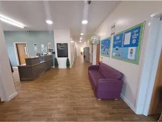 Bright school corridor with a reception desk, a purple sofa and colourful display boards