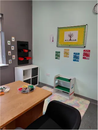 A quiet learning room with a desk, chair, storage shelves and wall displays