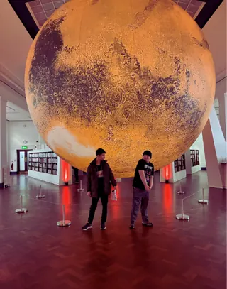 Pupils standing beneath a giant illuminated model of Mars on an educational visit
