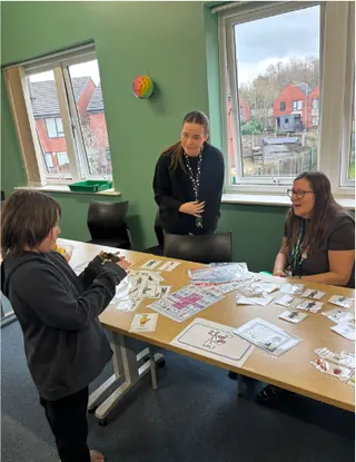 A pupil and two members of staff working together on a table-top learning activity