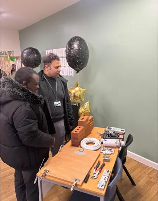 Visitors and staff at a school event, looking at a display of tools and building materials