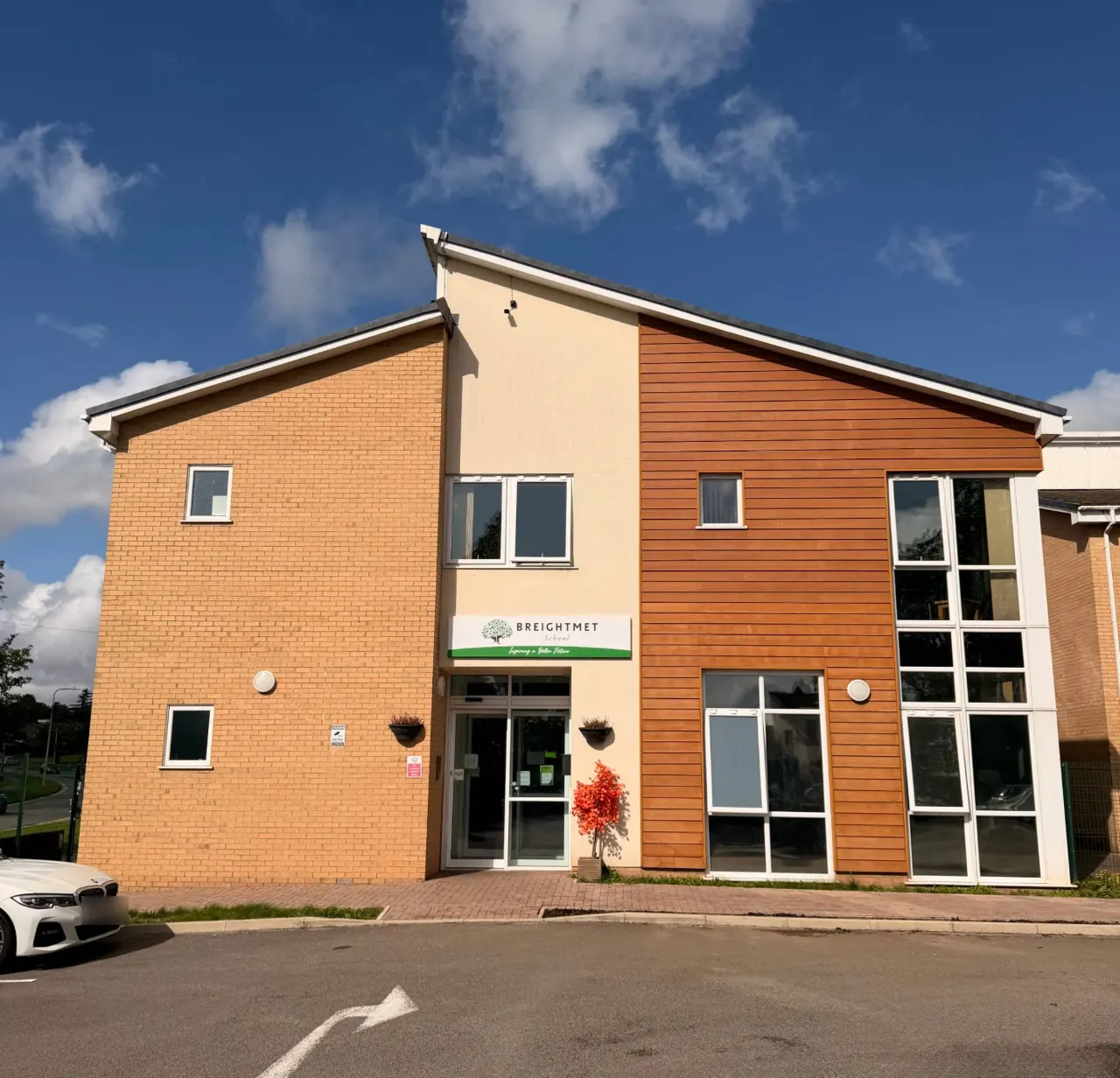 The front of Breightmet School: a modern brick and timber-clad building with the school sign above the entrance